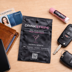 DrinkStrips packet on a table with a phone, wallet, keys, and ChapStick.